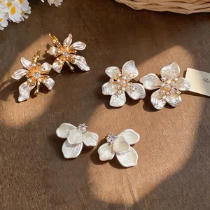 Elegant French style camellia pearl stud earrings with sparkling zircon on wood background