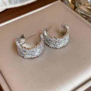 Close-up view of elegant silver C-shaped hoop earrings with shiny pavé cubic zircon stones