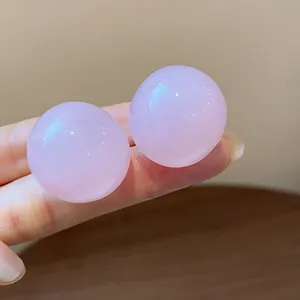Close-up of minimalist pink resin round stud earrings showing smooth glossy texture.