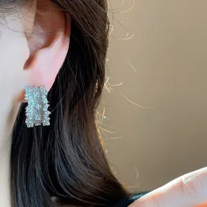 Detailed close-up of elegant silver needle zircon encrusted C-shaped earrings on ear