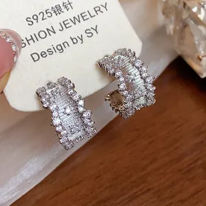 Macro detail of elegant C-shaped earrings with sparkling cubic zirconia on silver posts