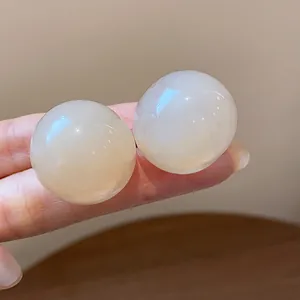 Close-up of minimalist round resin stud earrings with a translucent milky finish