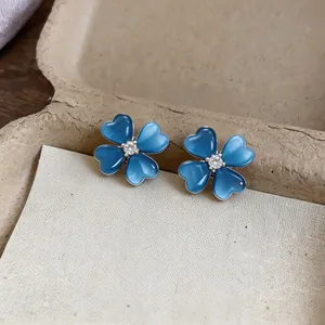 Macro detail of blue cat-eye flower stud earrings with a central zircon sparkling stone