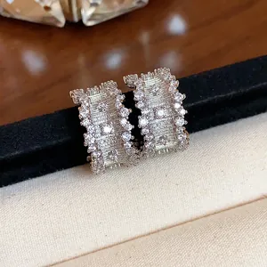 Macro detail of C-shaped silver needle earrings with shimmering zirconia accents