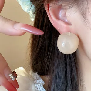 Detailed macro view showing the smooth texture of round cream resin stud earrings on ear