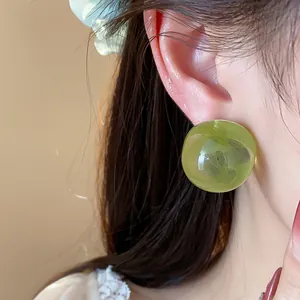 Detailed view of a green resin round stud earring with silver pin, minimalist style.