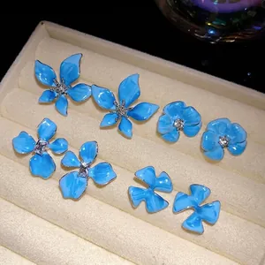 Elegant light blue enamel flower stud earrings with rhinestones arranged in a jewelry tray.