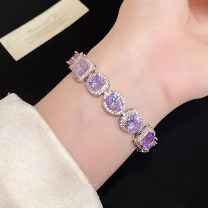 Detailed view of luxury silver bracelet with purple heart and oval zircons on wrist.