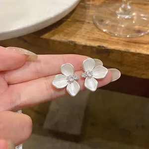 Detailed macro shot of French camellia earrings with zirconia and pearlescent petals.