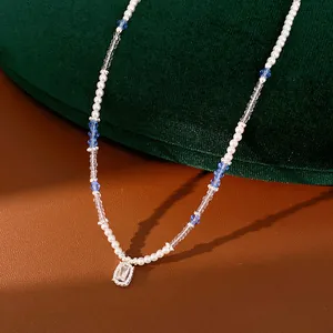 Close-up of beaded necklace with blue crystals, pearls, and rectangular zircon pendant