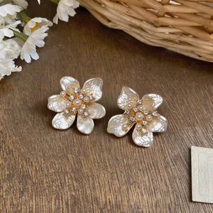Elegant French camellia flower earrings with pearls and zircons on wooden background