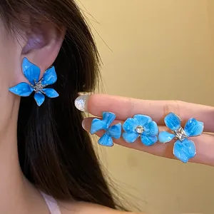 Detail of blue enamel flower earrings with sparkling rhinestones and silver needles