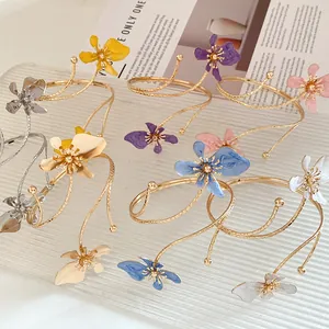 Détail de bracelets de bras en fleur métallique colorée avec finition émaillée.