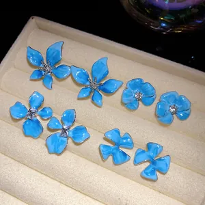 Detailed view of blue enamel flower stud earrings with sparkling central crystals.