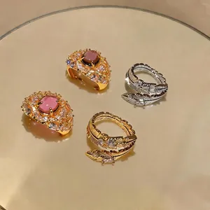 Elegante set di anelli placcati oro 18 carati con piume e pietre rosa su specchio.