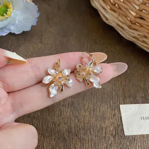 Detailed view of elegant gold-tone camellia earrings with zircons and white petals