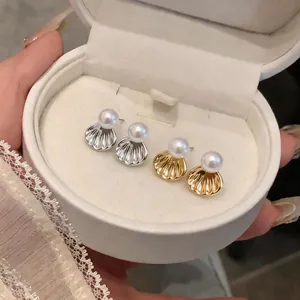 Gros plan sur des boucles d'oreilles perles et coquillages dans un coffret cadeau blanc