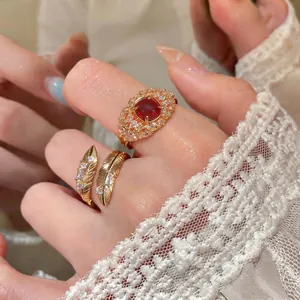 Anello con piuma in zircone placcato oro 18 carati e anello con gemma rossa su mano
