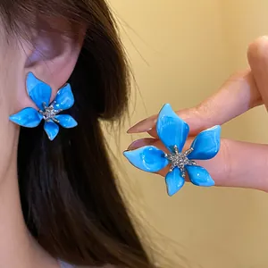 Close-up macro detail of elegant blue enamel flower earrings with a sparkling center