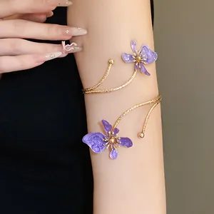 Gros plan d'un brassard spirale doré avec des fleurs en émail violet sur le bras