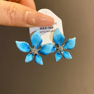 Detail of blue enamel flower stud earrings with shimmering rhinestone center