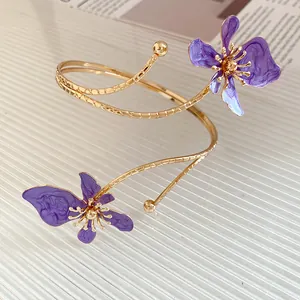 Gros plan d'un bracelet de bras doré orné de délicats motifs de fleurs en émail violettes