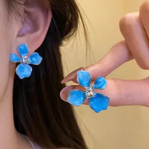 Detailed close-up of blue enamel flower stud earrings with sparkling CZ center