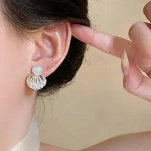 Gros plan détaillé d'une boucle d'oreille en perle en forme de coquillage sur l'oreille