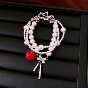 Elegant multi-layer pearl bracelet featuring red apple charm and zircon bow pendant