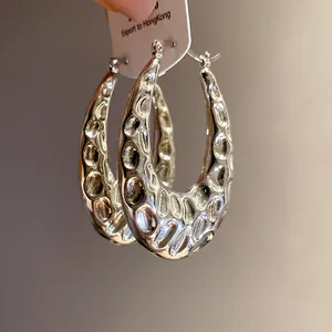 Primo piano di orecchini a cerchio vintage a forma di U in argento martellato.