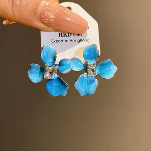 Detailed shot of blue enamel floral stud earrings with a clear cubic zirconia center