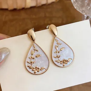 Elegant vintage teardrop earrings with gold floral branch pattern and pearl white resin inlay