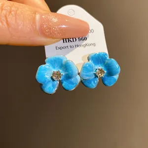 Detailed macro view of blue enamel flower stud earrings with a sparkling center rhinestone