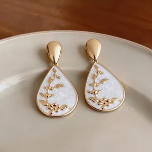 Elegant gold-plated teardrop earrings with white floral enamel inlay and vintage design