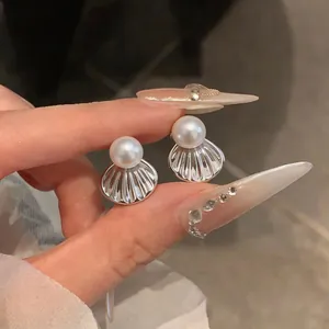 Gros plan sur d'élégantes boucles d'oreilles perles en forme de coquillage argenté chic