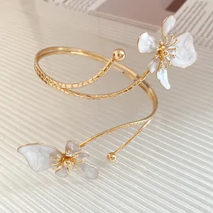 Vue détaillée d'un bracelet de bras doré avec d'élégantes fleurs en émail blanc