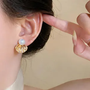 Détail d'une boucle d'oreille coquillage française avec perle. Éclairage doux.