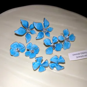 Detail view showing various blue enamel flower stud earrings with sparkly rhinestones