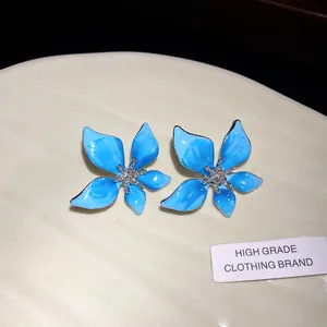 Detailed macro view of blue enamel flower earrings with sparkling rhinestone centers