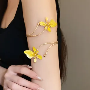 Détail d'un bracelet de bras doré avec fleurs en émail jaune porté par un modèle