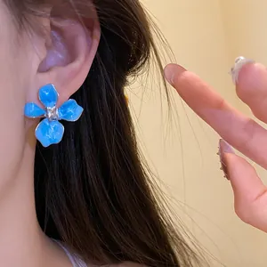 Close-up of elegant blue enamel flower stud earring with sparkling rhinestone center