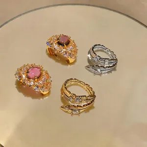 Vista dettagliata di anelli di lusso in piuma placcati oro 18K e pietre rosa con zirconi.