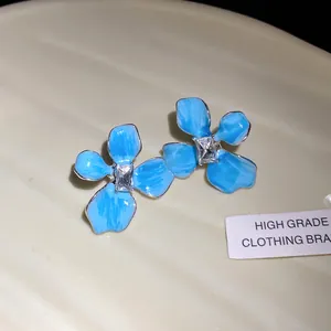 Close-up of elegant blue enamel flower stud earrings with a central square crystal