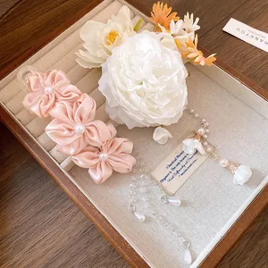 Close-up of elegant pink fabric flower hair clip with pearl tassels in jewelry box