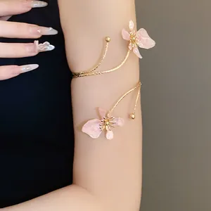 Gros plan d'un bracelet de bras en métal doré avec des fleurs en émail rose