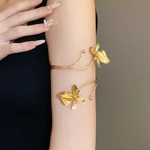 Détail d'un élégant bracelet de bras en métal doré avec des fleurs porté sur le bras