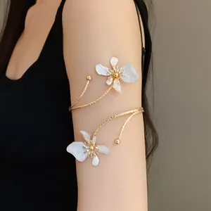 Vue détaillée d'un élégant bracelet de bras doré avec des fleurs en émail blanc