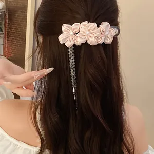 Detailed view of elegant pink fabric flower hair clip with pearl tassel on hair