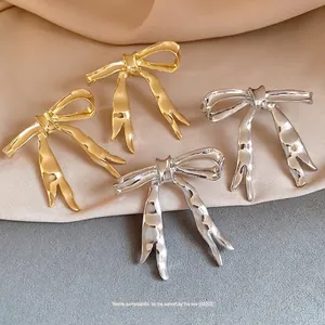 Elegant high-gloss metallic bow earrings in gold and silver finish, vintage minimalist style