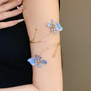 Vue détaillée d'un bracelet de bras en métal doré avec d'élégantes fleurs émaillées bleues.
